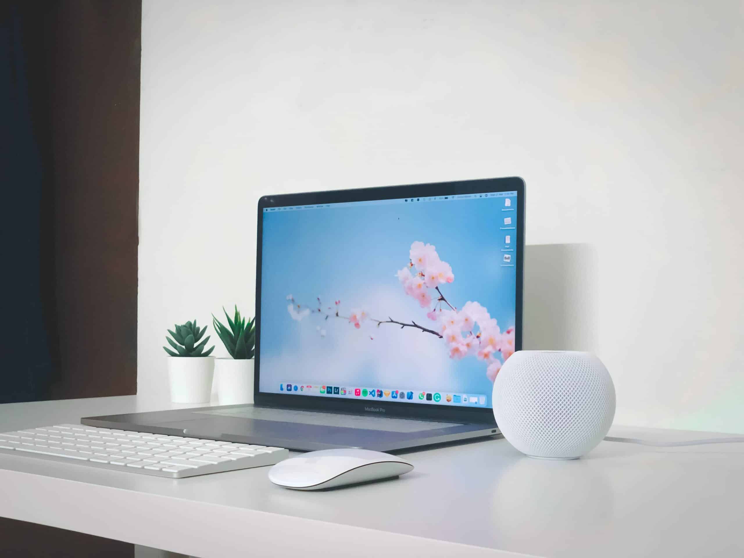 Home Pod mini with a MacBook Pro on a desk